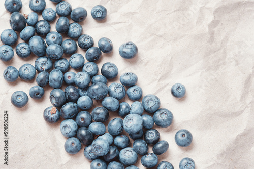 Fresh blueberries scattered on beige craft paper.