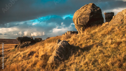 Sunset landscape of large rocks on a golden hillside against a cloudy sky