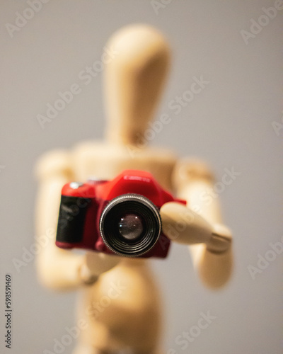 Close up of a wooden mannequin holding a camera