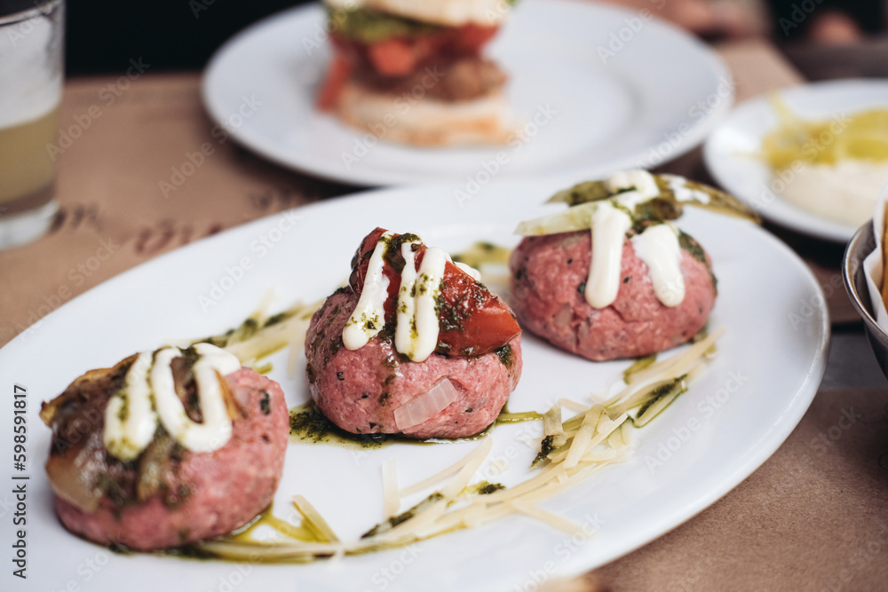 Traditional Chilean meal - crudo - raw meat balls with onions, spices, mayonnaise. tomatoes on a table in a restaurant Traditional Chilean meal - crudo - raw meat balls with onions, spices, mayonnaise. tomatoes on a table in a restaurant