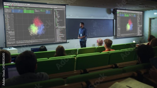 Young University Professor Explaining the Importance of Artificial Intelligence to a Group of Diverse Students in a Modern Auditorium. Teacher Showing a Neural Network Model on a Big Screen photo