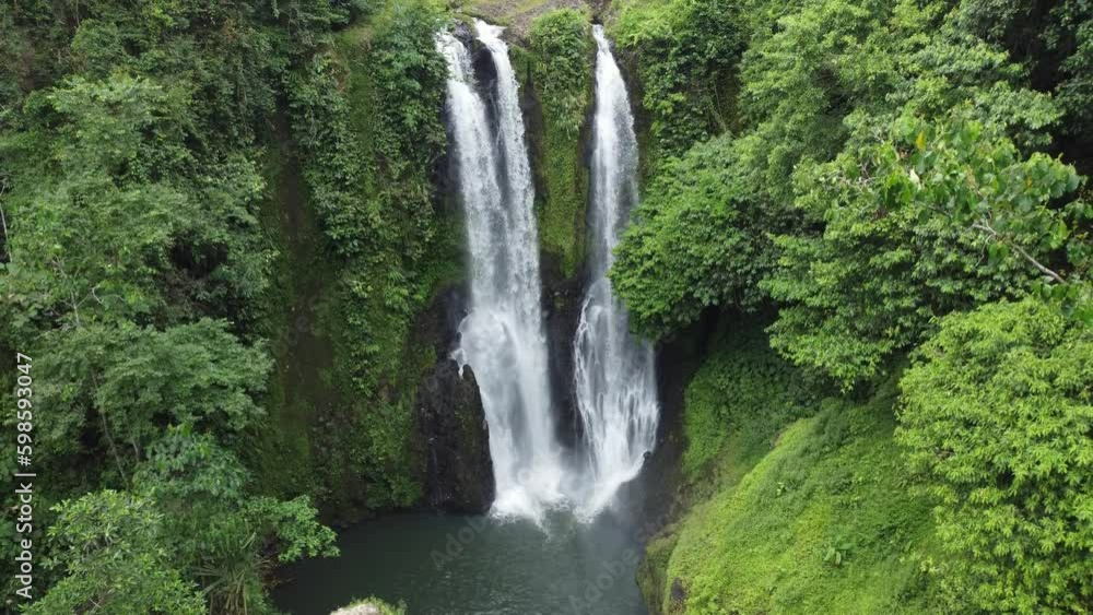 The beautiful scenery of Blang Kolam Waterfall surrounded by trees is captured from an aerial perspective. The beautiful scenery of Blang Kolam Waterfall surrounded by trees is captured from an aerial perspective.