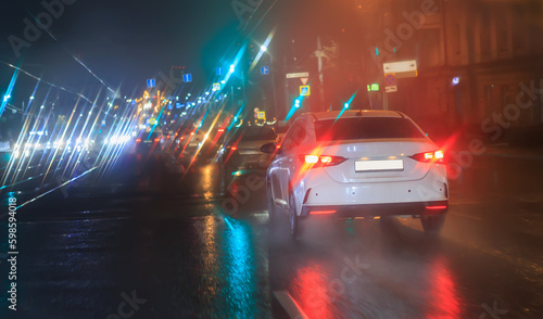 Car traffic at night in the rain on a city