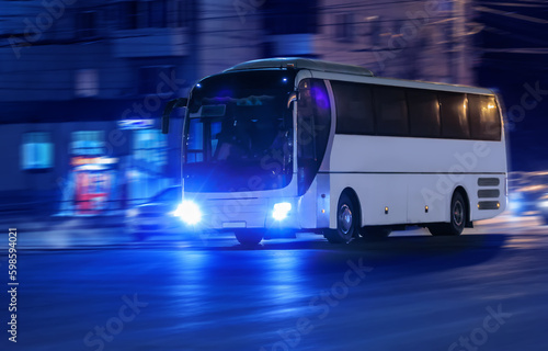 Tourist bus moves at night along the city street.