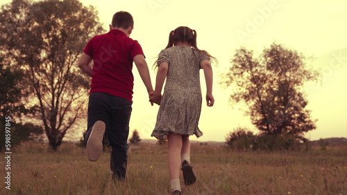 child kid run sunset. cheerful boy girl. happy son daughter friends. running childhood. happy family. cheerful happy day. dream. hold hand sister. green lawn. sunset evening. vintage. chidhood dream