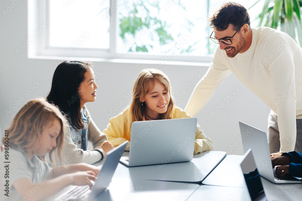 Computer-based learning in an elementary school: Teacher guiding a group of students in a coding class Computer-based learning in an elementary school: Teacher guiding a group of students in a coding class
