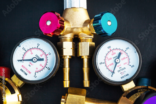 New cutter and two monometers for acetylene and oxygen, for gas cutting of metal. New torch for gas cutting. Gas cutting equipment on a black background.