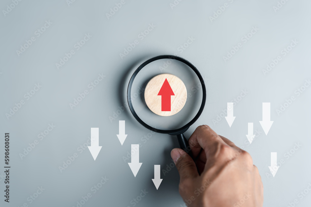 Hand holding magnifier focus to Red arrow and different direction facing opposite direction with