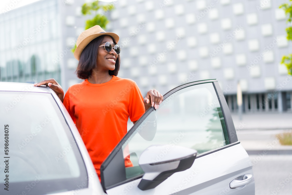 Naklejka premium Adventures in the city: black woman with sunglasses and orange shirt getting into car