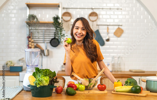 Portrait of beauty body slim healthy asian woman having fun cooking and preparing vegan food healthy eat with fresh vegetable salad, apple in kitchen at home.Diet concept.Fitness and healthy food