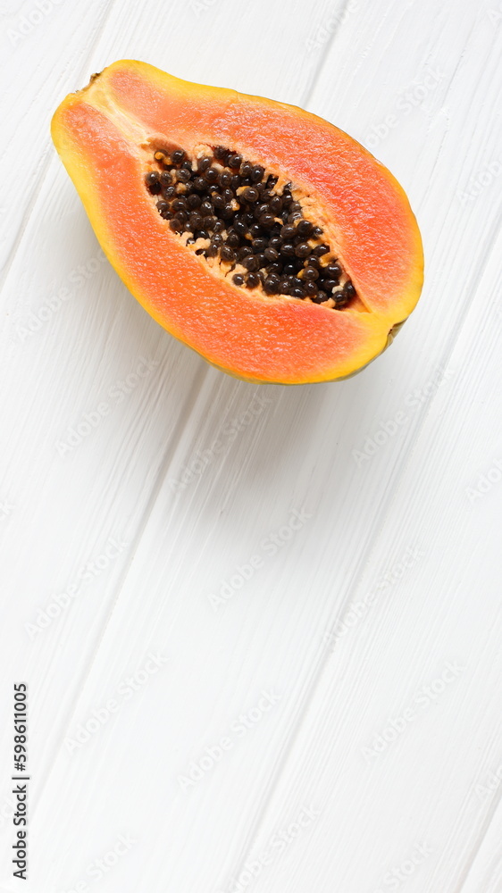 Half of papaya fruit on white wooden table Half of papaya fruit on white wooden table