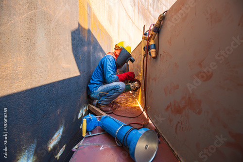Male worker wearing protective clothing and repair grinding storage tank