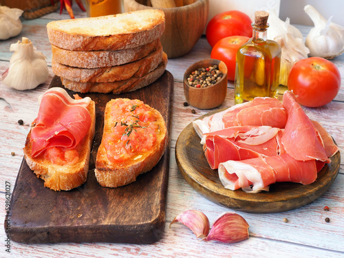 Tapas and ingredients on a wooden board. Toasts with tomatoes and ham photo