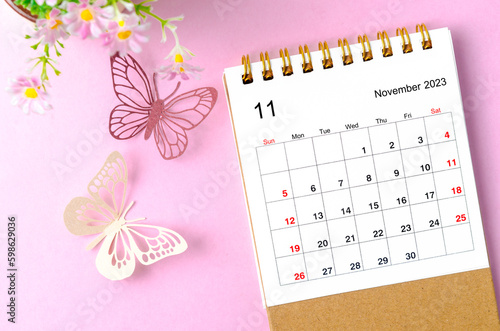 A November 2023 desk calendar for the organizer to plan and reminder and paer butterfly on pink colour background. photo