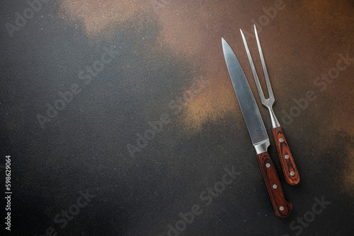 meat knife and barbecue fork on old board on concrete background. ingredients for grilling meat steak. Long banner format. top view