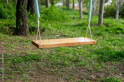 Close- up of a swing in motion with forest cover in the background symbolizing fun, children s play area and freedom photo