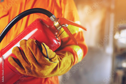 hand presses the trigger fire extinguisher available in fire emergencies conflagration damage background. Safety photo