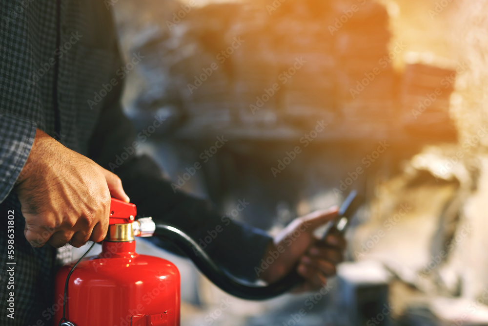 hand presses the trigger fire extinguisher available in fire emergencies conflagration damage background. Safety hand presses the trigger fire extinguisher available in fire emergencies conflagration damage background. Safety
