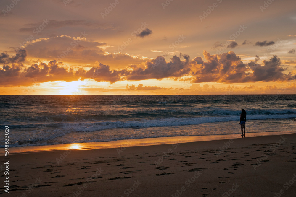 Chinese woman on the beach against a spectacular ocean sunset in Phuket