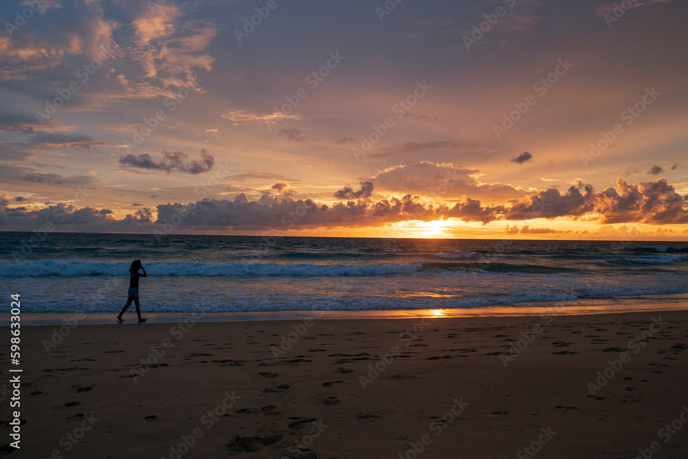 Chinese woman on the beach against a spectacular ocean sunset in Phuket