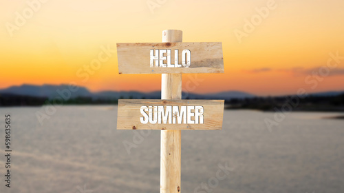 Hello summer symbol. Wooden sign board on blurry sea or lake background with hello summer text on it.