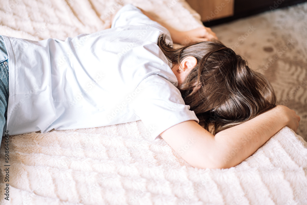 Upset lady in a white t-shirt lies on the bed. Upset lady in a white t-shirt lies on the bed.