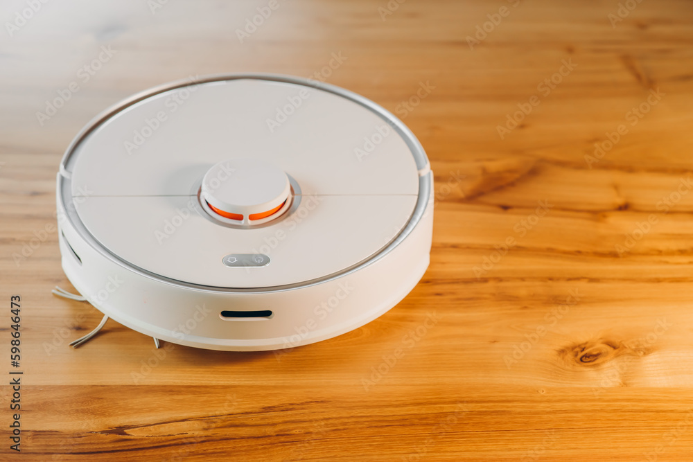 Robot vacuum cleaner on a wooden floor. The view from the front. Smart home. The concept of a home assistant. Robot vacuum cleaner on a wooden floor. The view from the front. Smart home. The concept of a home assistant.