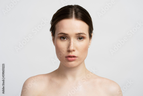 Young beautiful confident woman looking in mirror after shower isolated on white background. Beauty, morning routine concept 
