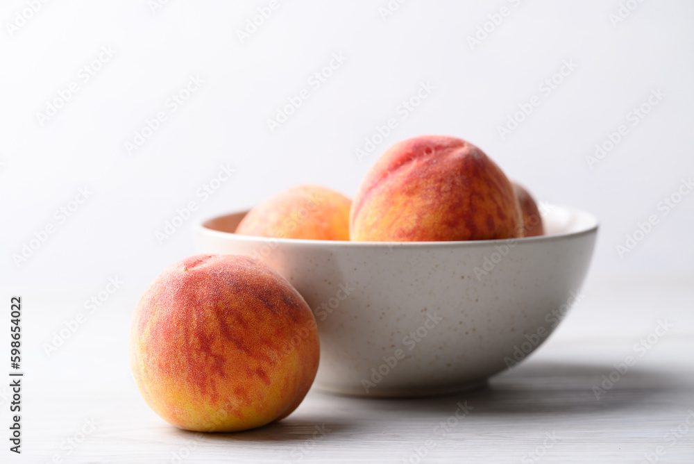 Ripe Peaches fruit in bowl on white table Ripe Peaches fruit in bowl on white table