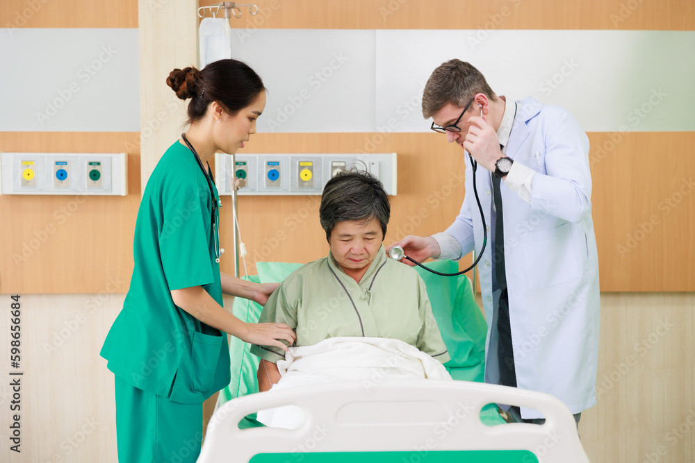 Obraz premium senior woman patient lying in hospital bed and doctor team working at hospital ward. Healthcare medical and medicine concept.