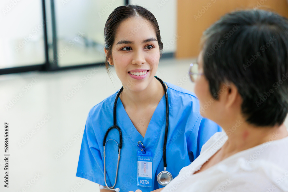 Young asian doctor in blue uniform and senior woman holding hands together. Positive Asian woman caregiver helping patient. Young asian doctor in blue uniform and senior woman holding hands together. Positive Asian woman caregiver helping patient.