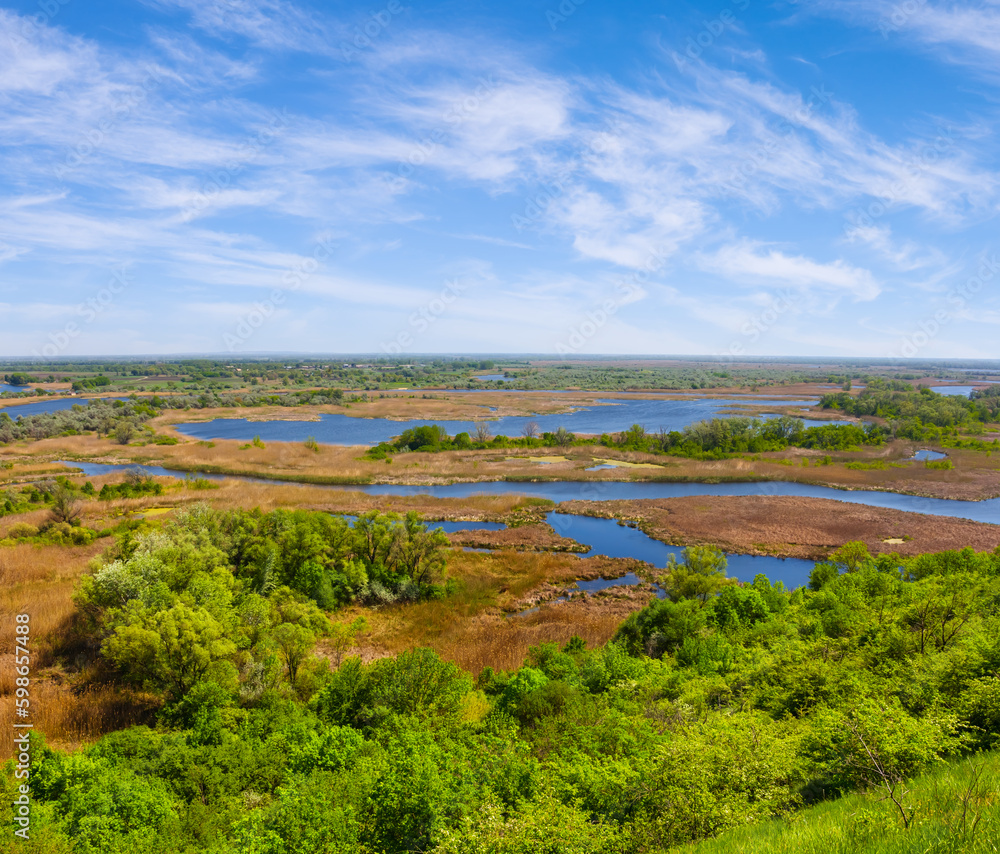 Obraz premium view fhom green hill to the blue river among prairie under blue cloudy sky