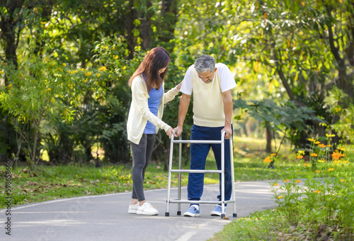 caregiver takes disability senior man practice walking with walker in the park