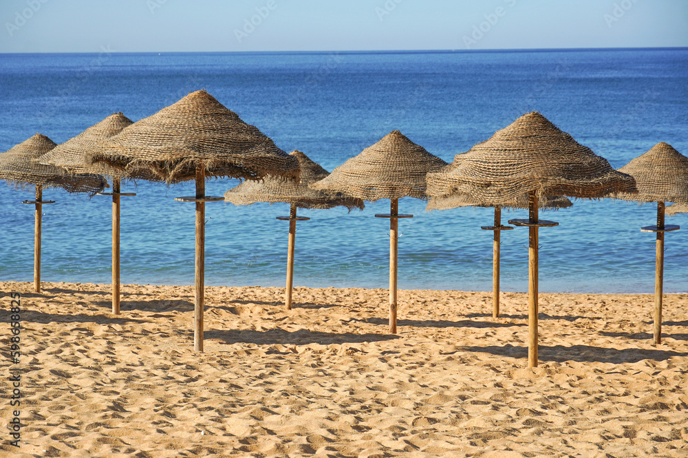straw beach umbrellas at the beach with blue ocean