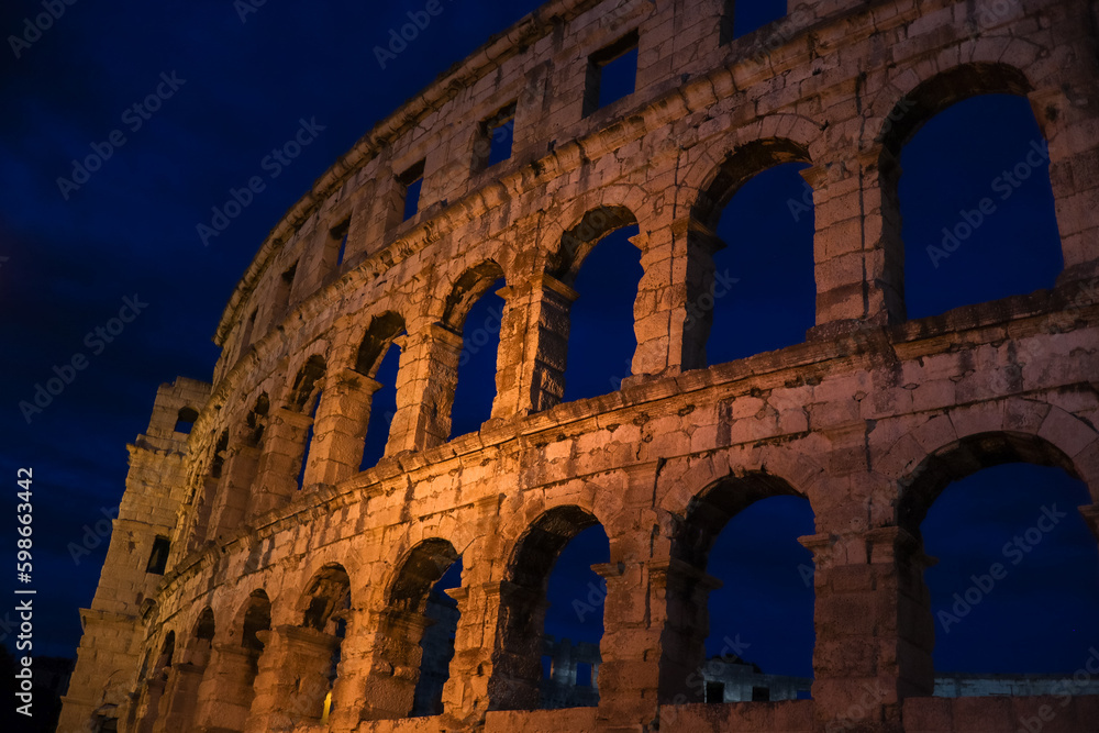 Beautiful Pula Arena at Night. European Historical Landmark with Evening Sky. Roman Amphitheater with Arch in Istria.