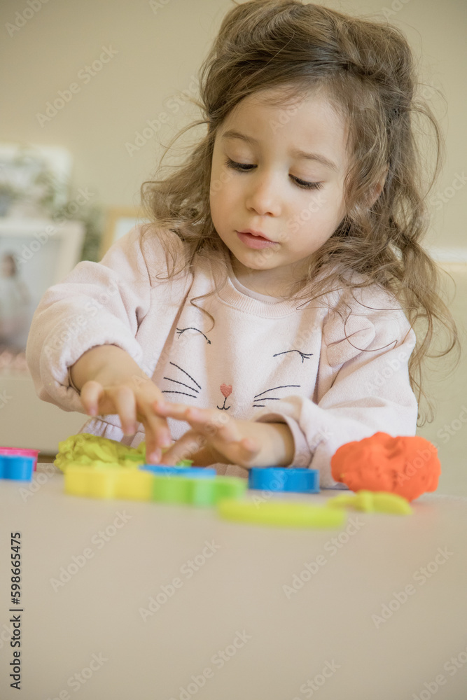 Caucasian child, two or three years old, playing and exercising fine motor skills with her hands, with clay and colored plasticine. Concept of happy childhood, learning and creativity. Copy space Caucasian child, two or three years old, playing and exercising fine motor skills with her hands, with clay and colored plasticine. Concept of happy childhood, learning and creativity. Copy space