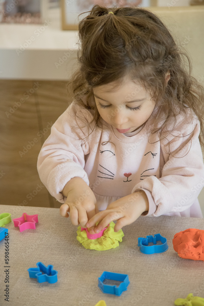 Caucasian child, two or three years old, playing and exercising fine motor skills with her hands, with clay and colored plasticine. Concept of happy childhood, learning and creativity. Copy space Caucasian child, two or three years old, playing and exercising fine motor skills with her hands, with clay and colored plasticine. Concept of happy childhood, learning and creativity. Copy space