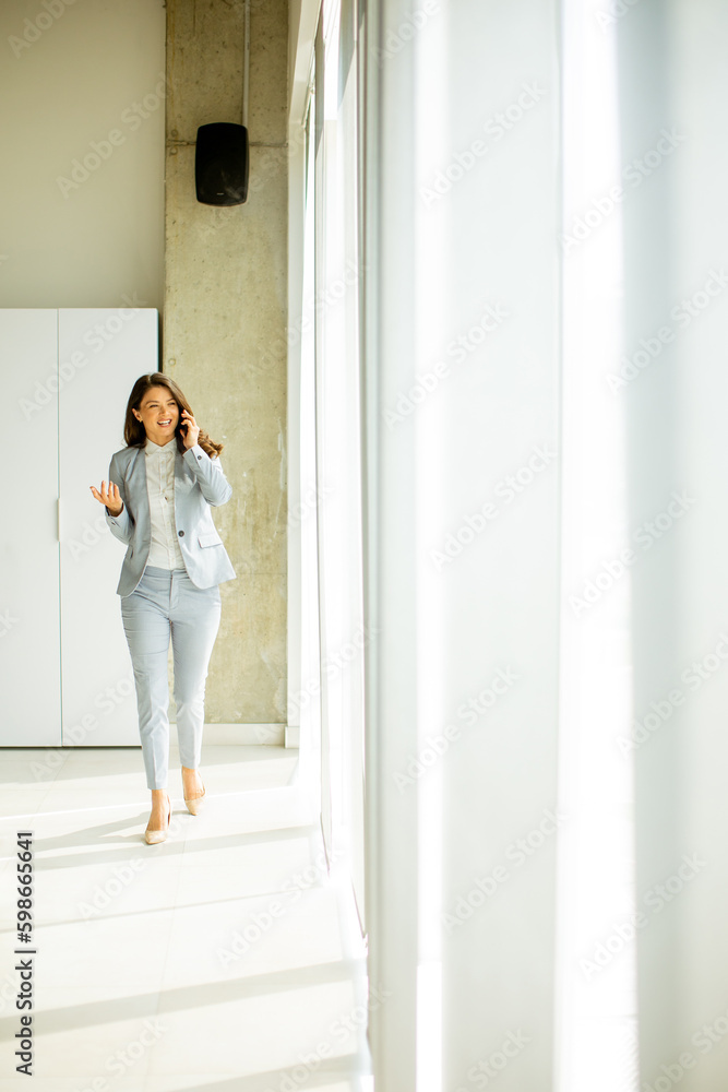 Young woman with mobile phone by the window Young woman with mobile phone by the window