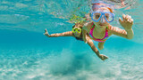 Young mother with child in snorkeling mask dive in coral reef sea lagoon to explore underwater world. Family travel lifestyle in summer adventure camp. Swimming activities on beach vacation with kids.