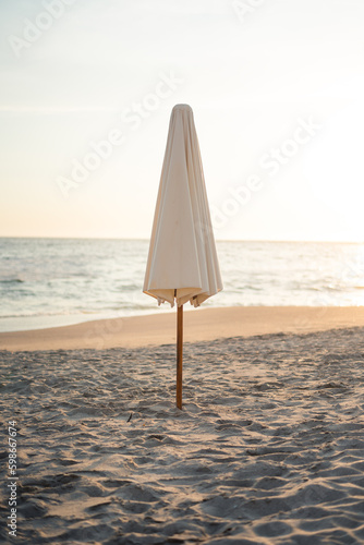Closed umbrella on the beach in the afternoon
