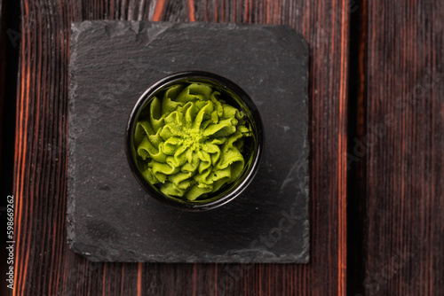 Obraz na plátne Green wasabi sauce or paste in bowl on wooden background top view