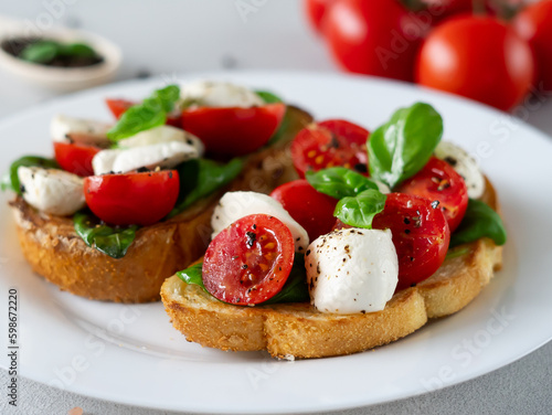 Close-up of Caprese Bruschetta with fresh tomatoes, mozzarella and Basil leaves on light background. Vegetarian food