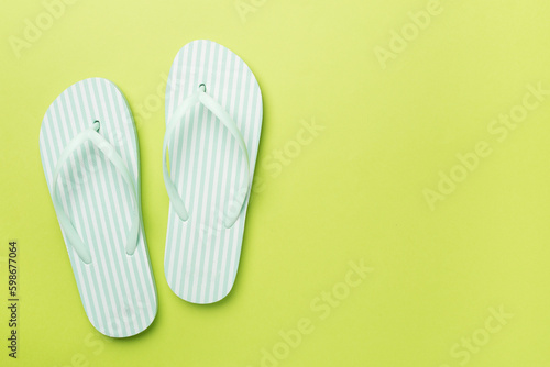 Striped flip flops on color background, top view