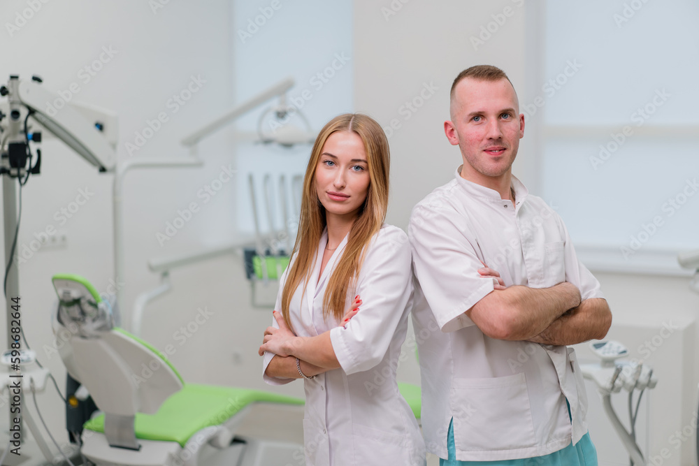 Obraz premium portrait of beautiful young smiling colleagues of dentists standing in the dental office before the start of the procedure