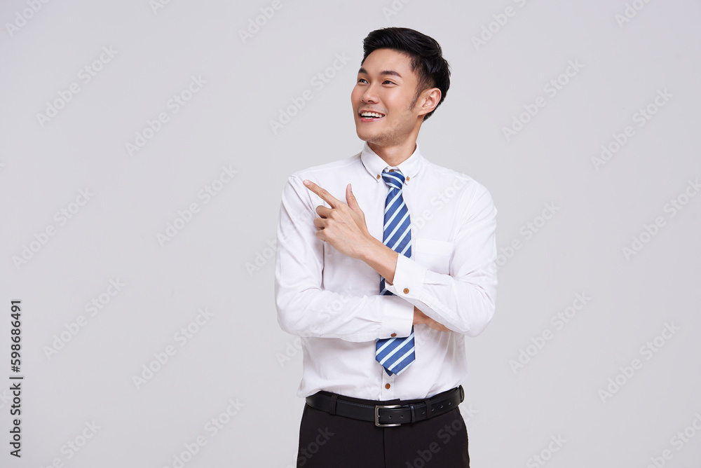 Happy smiling Asian businessman pointing finger to empty copy space isolated on white studio background. Happy smiling Asian businessman pointing finger to empty copy space isolated on white studio background.