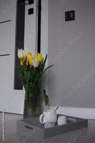 A vase with yellow and white near interior door and cup of coffee. Modern room