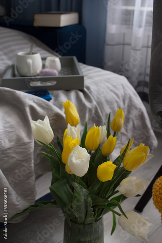 A pleasant morning with coffee and a bouquet of white and yellow tulips. A surprise in the bed