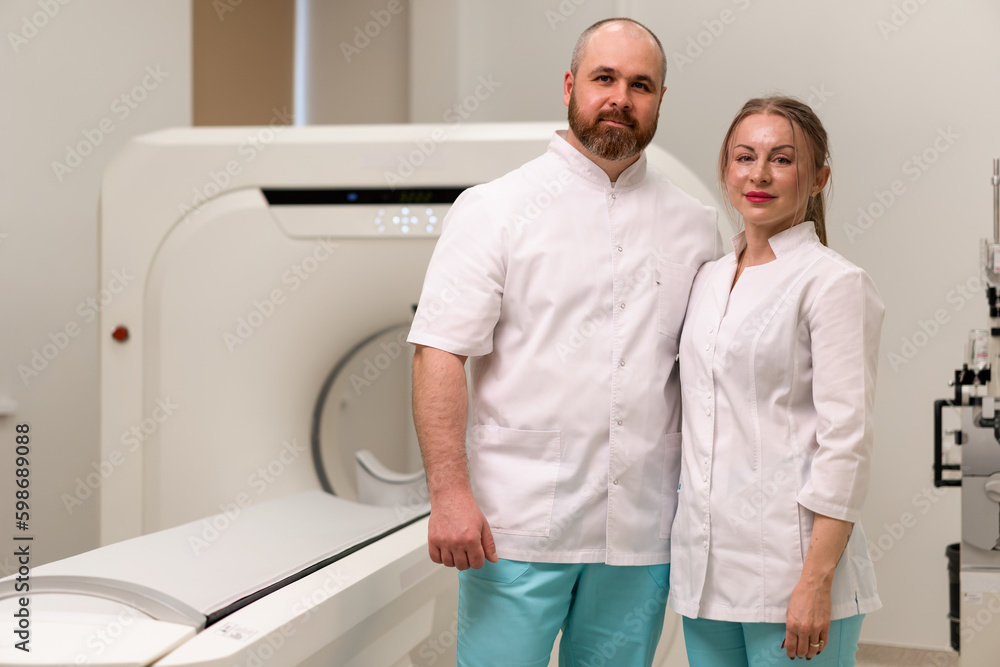 Obraz premium smiling and satisfied doctors in uniform posing near magnetic resonance imaging machine concept of professions and medicine