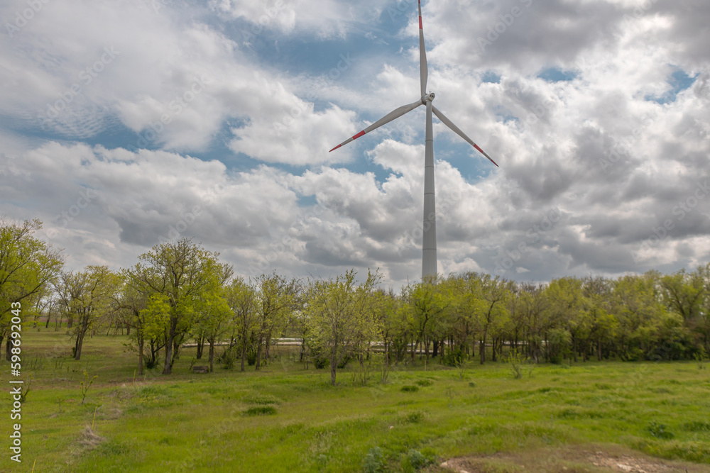 Fototapeta premium Wind turbines on the background of a summer landscape with blue sky, white clouds