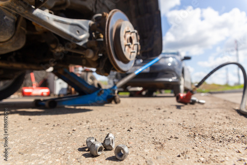 Car on tire mounting with removed wheel on pneumatic jack, seasonal tire change, car service concept.